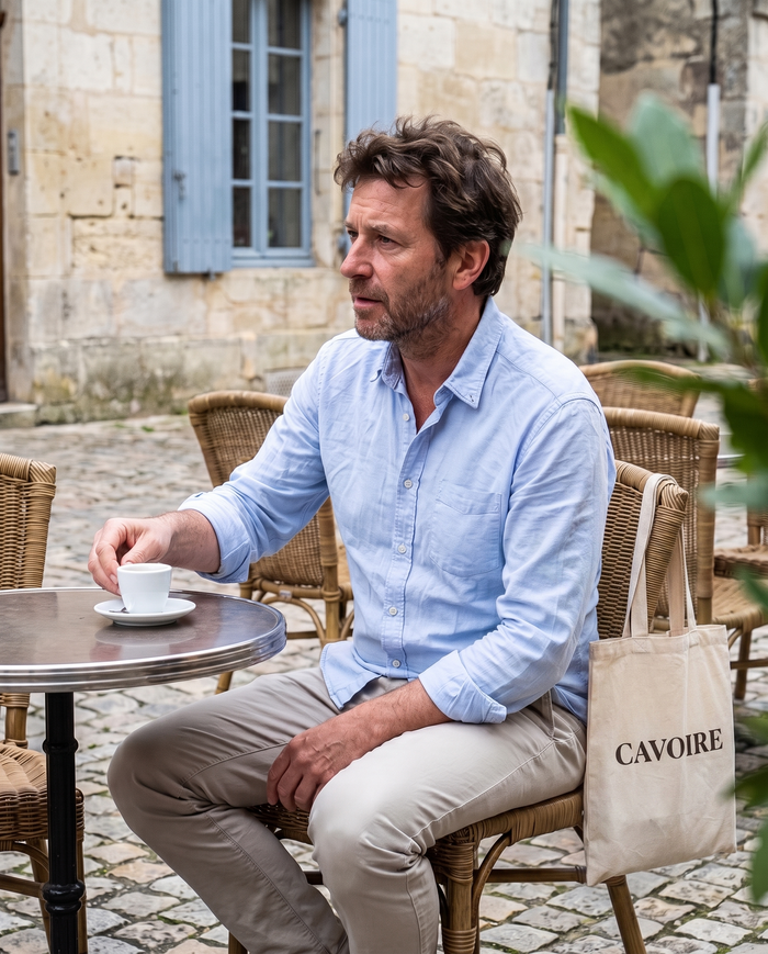 Homme en chemise bleu pâle à la terrasse d'un café de village